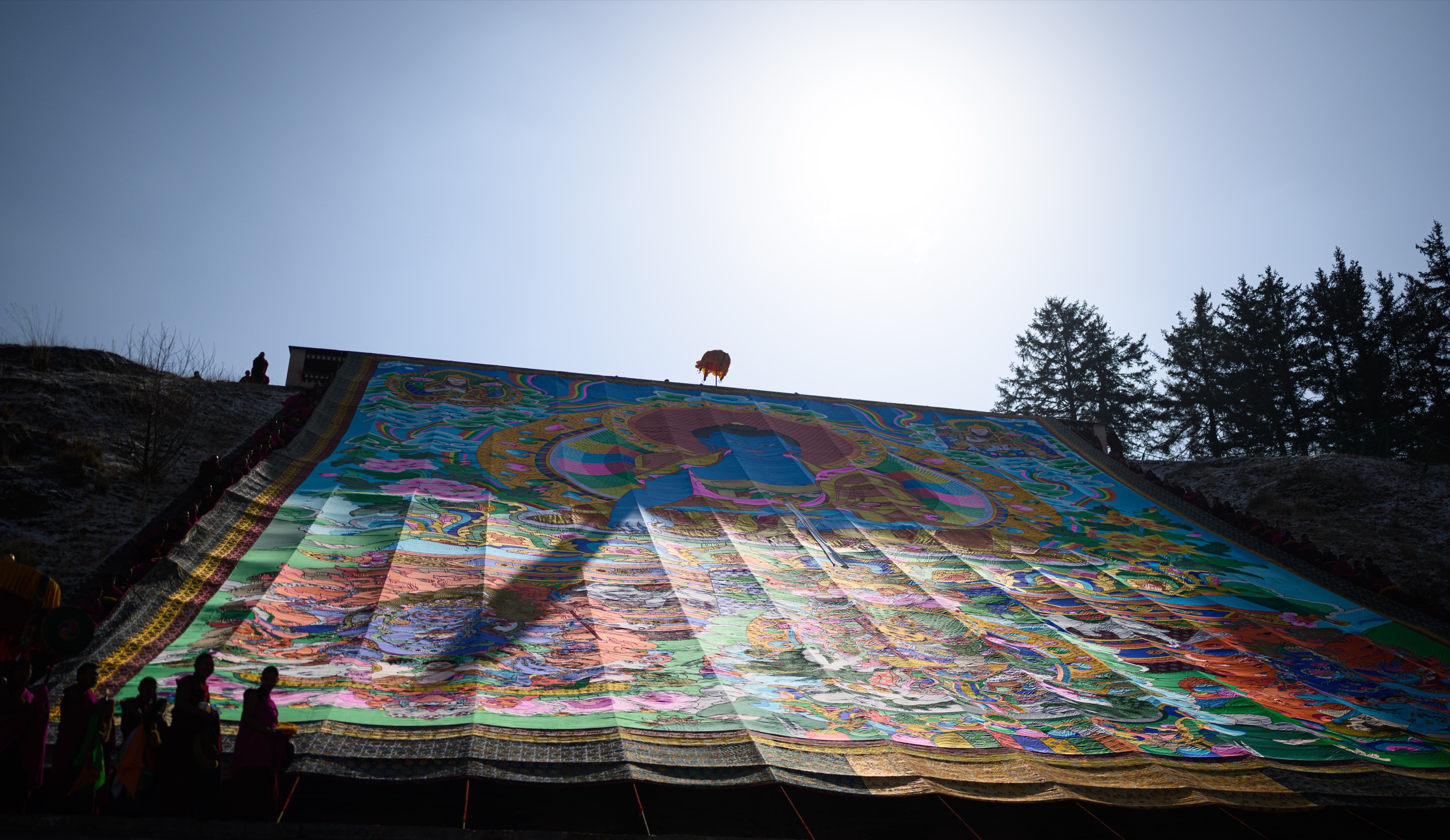 The monumental thangka fully unfurled on the hillside